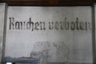 Dachau toplama kampı kapısının görüntüsü, tarihsel öneme sahip bir amblem ve demirden yapılmış gölgeleriyle kasvetli bir hatıra. Yüksek kalite fotoğraf