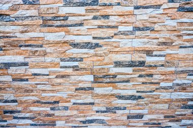 Görüntü, katmanlı, çok renkli taşlardan oluşan taş bir duvar sergiliyor, zengin ve dokulu bir görünüm yaratıyor. Yüksek kalite fotoğraf