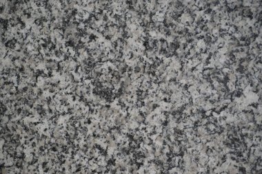 Gri tonlu kaba granit taşın yakın çekim dokusu ayrıntılı bir pürüzlü yüzeyi gösteriyor. Yüksek kalite fotoğraf