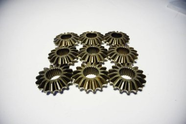 Temiz beyaz arkaplan ve hassas mühendislik parçalarını gösteren dokuz adet benzer metal eğim dişlisi şebekeye yerleştirilmiş. Yüksek kalite fotoğraf