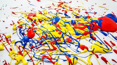 Renkli boya, beyaz bir yüzeye kırmızı, mavi ve sarı renkte sıçrayan soyut bir bileşim yayarak dinamik ve sanatsal bir şekil yaratır. Yüksek kalite fotoğraf