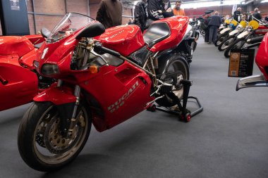 Modea, İtalya: 2025 03 30 Motor Festivali Fuarı Motosiklet A klasik Ducati 916 motosiklet ve kırmızı ve beyaz üniforma bir motosiklet fuarında sergilenmektedir. Yüksek kalite fotoğraf