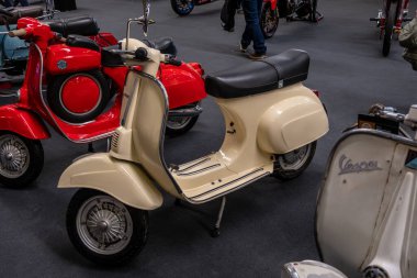 Modea, İtalya: 2025 03 Motor Festivali Fuarı Motosiklet Fuarı ön planda krem renkli bir mobilet de dahil olmak üzere çeşitli vintage Vespa scooter 'lar kapalı bir alanda park edilmiş ve sembolik İtalyan scooter tasarımı sergilenmektedir. Yüksek kalite fotoğraf