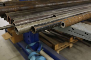 Yakın plan çekimde İtalya 'da endüstriyel bir ortamda bulunan uzun ve koyu metal borular, hammadde veya üretilmiş bileşenleri gösteriyor. Yüksek kalite fotoğraf