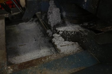 Yakından bakınca, İtalya 'daki bir atölyedeki karanlık bir endüstriyel kesme makinesinin etrafında toplanan metal talaşı ve talaş görülüyor. Bu da metal işleme süreçlerini gösteriyor. Yüksek kalite fotoğraf