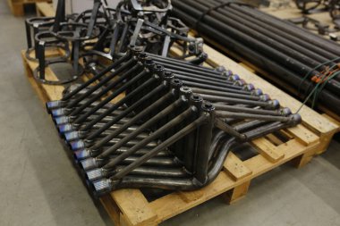 Birden fazla siyah metal çerçeve İtalya 'da bir depoda ya da fabrikada işlenmeye hazır ahşap bir paletin üzerine düzgünce istiflenmiştir. Yüksek kalite fotoğraf