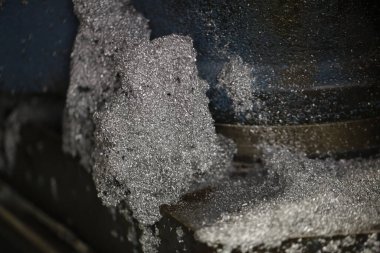Yakından bakınca, İtalya 'daki bir atölyedeki karanlık bir endüstriyel kesme makinesinin etrafında toplanan metal talaşı ve talaş görülüyor. Bu da metal işleme süreçlerini gösteriyor. Yüksek kalite fotoğraf