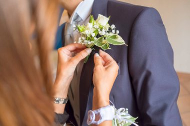 İtalya 'da bir kadın, mavi takım elbiseli bir damadın yakasına beyaz bir gül ve bebek nefesi yaka iğnesi takar ve bir düğün törenine hazırlanır. Yüksek kalite fotoğraf