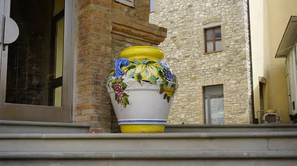 Geleneksel el yapımı üzüm ve yapraklarla süslenmiş büyük, renkli bir vazo klasik bir İtalyan binasının dışındaki taş basamaklarda duruyor. Yüksek kalite fotoğraf