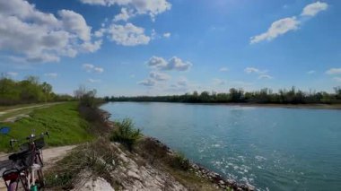  İtalya 'nın Cremona yakınlarındaki Po Nehri' nin geniş, sakin manzarası yemyeşil bankalar, uzak ağaçlar ve seyrek bulutlu açık mavi bir gökyüzü..