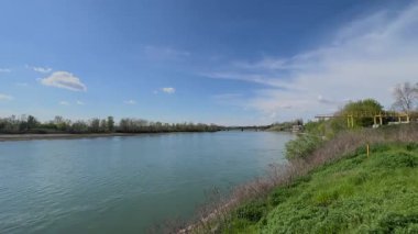  İtalya 'nın Cremona yakınlarındaki Po Nehri' nin geniş, sakin manzarası yemyeşil bankalar, uzak ağaçlar ve seyrek bulutlu açık mavi bir gökyüzü..
