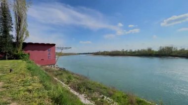  İtalya 'nın Cremona yakınlarındaki Po Nehri' nin geniş, sakin manzarası yemyeşil bankalar, uzak ağaçlar ve seyrek bulutlu açık mavi bir gökyüzü..