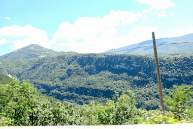 İtalya 'nın Abruzzo kentindeki Pescasseroli yakınlarında bulunan doğal güzelliğin tipik bir örneği olarak, berrak bir gökyüzü altında yuvarlanan yeşil tepelerin ve ormanların geniş panoramik manzarası. Yüksek kalite fotoğraf