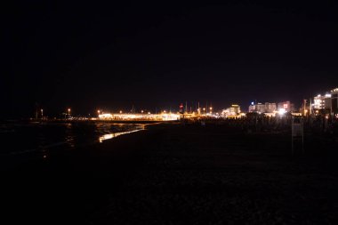 Geceleri Cesenatico plajı, kıyı şeridi otellerin ve işletmelerin uzak ışıklarını yansıtarak parlayan bir deniz manzarası yaratıyor. Yüksek kalite fotoğraf