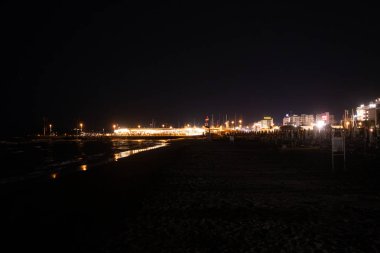 Geceleri Cesenatico plajı, kıyı şeridi otellerin ve işletmelerin uzak ışıklarını yansıtarak parlayan bir deniz manzarası yaratıyor. Yüksek kalite fotoğraf