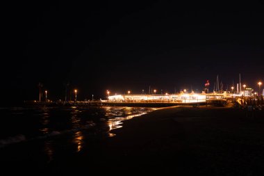 Geceleri Cesenatico plajı, kıyı şeridi otellerin ve işletmelerin uzak ışıklarını yansıtarak parlayan bir deniz manzarası yaratıyor. Yüksek kalite fotoğraf