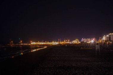 Geceleri Cesenatico plajı, kıyı şeridi otellerin ve işletmelerin uzak ışıklarını yansıtarak parlayan bir deniz manzarası yaratıyor. Yüksek kalite fotoğraf