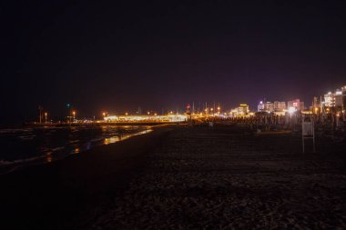 Geceleri Cesenatico plajı, kıyı şeridi otellerin ve işletmelerin uzak ışıklarını yansıtarak parlayan bir deniz manzarası yaratıyor. Yüksek kalite fotoğraf
