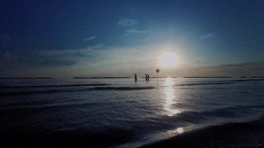 Güneş Adriyatik Denizi 'nin üzerinde şafak vakti Rimini' de yükselir, suya altın bir yansıma yapar ve sakin bir sahil manzarası yaratır. Yüksek kalite 4k görüntü