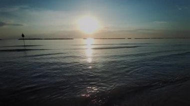 Güneş Adriyatik Denizi 'nin üzerinde şafak vakti Rimini' de yükselir, suya altın bir yansıma yapar ve sakin bir sahil manzarası yaratır. Yüksek kalite 4k görüntü