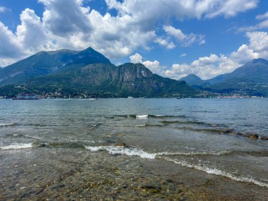 Como Gölü 'nün huzurlu manzarası. Arka planda dağ ve bulutlu bir gökyüzü. Ön planda dekoratif bir korkulukla çerçevelenmiş..