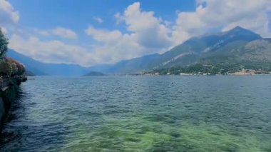 Como Gölü 'nün huzurlu manzarası. Arka planda dağ ve bulutlu bir gökyüzü. Ön planda dekoratif bir korkulukla çerçevelenmiş..