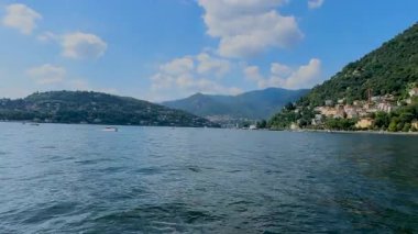 Como Gölü 'nün huzurlu manzarası. Arka planda dağ ve bulutlu bir gökyüzü. Ön planda dekoratif bir korkulukla çerçevelenmiş..