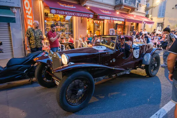 Parma, İtalya: 2025 06 20 Mille Miglia klasik rali klasik araba yarışı, klasik mavi bir yarış arabası açık hava kafesinde yemek yiyen insanlarla dolu bir caddede ilerliyor. Yüksek kalite fotoğraf