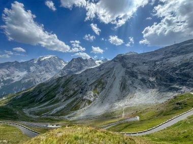 Ünlü Stelvio Geçidi 'nin dolambaçlı dağ yollarının panoramik bir görüntüsü. Görkemli tepelerin ve bulutlu gökyüzünün zeminine kurulmuş. Yüksek kalite fotoğraf