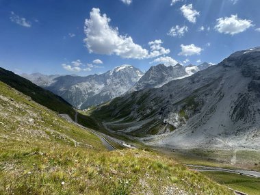 Ünlü Stelvio Geçidi 'nin dolambaçlı dağ yollarının panoramik bir görüntüsü. Görkemli tepelerin ve bulutlu gökyüzünün zeminine kurulmuş. Yüksek kalite fotoğraf