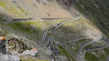 Ünlü Stelvio Geçidi 'nin dolambaçlı dağ yollarının panoramik bir görüntüsü. Görkemli tepelerin ve bulutlu gökyüzünün zeminine kurulmuş..
