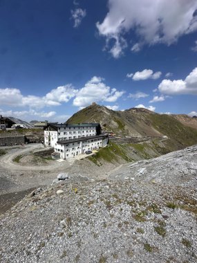 Stelvio Geçidi 'nde bir dağ kulübesi manzarası, zirvede bir binaya giden virajlı bir yol. Yüksek kalite fotoğraf