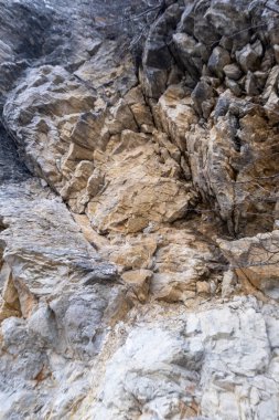 Çatlaklar, çatlaklar ve açık renk mineral çizgileriyle karışık ve detaylı bir dokuyu gösteren engebeli bir kaya yüzeyinin yakından görüntüsü. Yüksek kalite fotoğraf