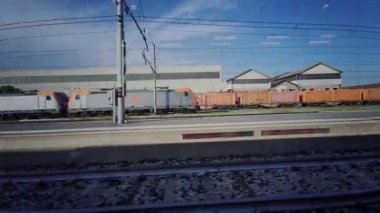 Endüstriyel binaları olan tren raylarının penceresinden bir manzara ve arka planda parlak bir gökyüzünün altında eski bir su kulesi. Yüksek kalite 4k görüntü