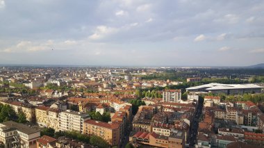 Torino siluetinin panoramik bir görüntüsü, bulutların arasından süzülen güneş ışınları ve arka planda görünen görkemli Alpler. Yüksek kalite fotoğraf