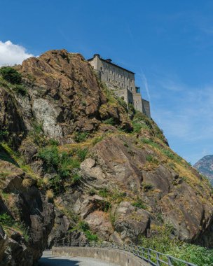 Ozan 'ın görkemli kalesi, muazzam bir askeri yapı, İtalya' nın Aosta Vadisi 'ndeki berrak mavi gökyüzünün altında kayalık bir uçurumun kenarında duruyor. Yüksek kalite fotoğraf