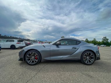 Modena ,Italy : 2023 05 13 A low-angle front view of a modern grey Toyota GR Supra sports car. The aggressive design is showcased in a parking lot under a dramatic, cloudy sky. High quality photo