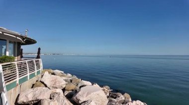 People on a stand-up paddleboard SUP on the calm, flat sea in Cesenatico, Italy. A peaceful and serene scene of water sports, leisure, and summer holidays. High quality 4k footage