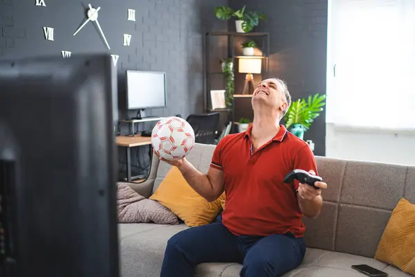 中年白人男子在家里玩足球电玩 — 图库照片