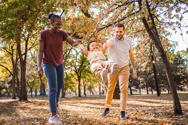 Χαρούμενη Κούνια Ανάμεσα Στους Γονείς Στο Πάρκο — Φωτογραφία Αρχείου