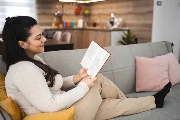 Mulher Lendo Livro Enquanto Relaxa Sofá Casa — Fotografia de Stock