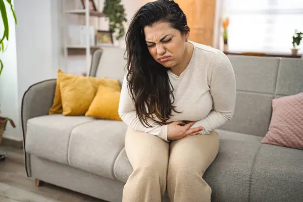 Woman experiencing painful stomachache at home.