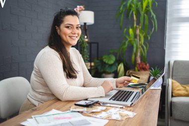 Gülümseyen kadın evde bilgisayardan alışveriş yapıyor..