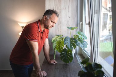 Pencerenin yanında duran adam üzgün ve perişan görünüyor..