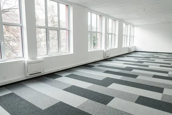 stock image Empty office space with a checkered floor and large windows letting in natural light. The space appears spacious and bright, with no furniture in sight. The checkered floor adds a classic touch to the