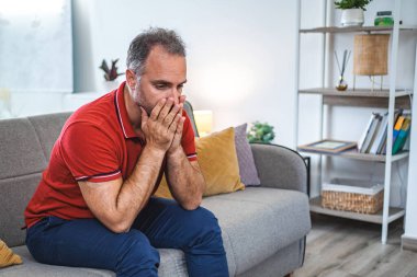 Evde tek başına oturan adam üzgün ve perişan görünüyor..