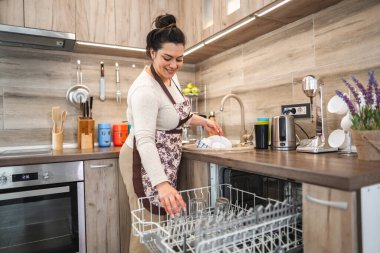 Mutfakta bulaşık makinesini dolduran kadın..