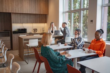 Farklı bireylerden oluşan bir grup, parlak ışıklı bir odadaki dikdörtgen bir masanın etrafında oturmaktadır. Önlerine dizüstü bilgisayarlar ve kağıtlar serilmiş bir tartışmayla meşguller. Bu oda...