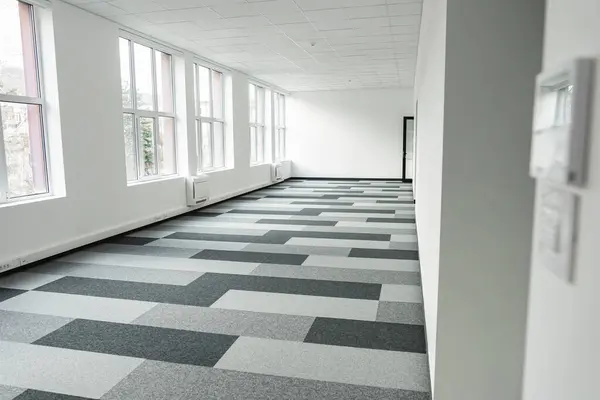 stock image Empty office space featuring a checkered floor and multiple windows that allow natural light to filter in. The space appears to be devoid of furniture or decoration, creating a stark and minimalist