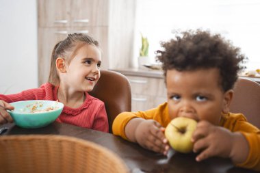 İki çocuk, gülümseme ve yemekle eğlenceli bir kahvaltı anını paylaşıyor..